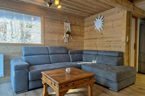 a living room with a blue couch and a coffee table at Magnifique chalet Nordique à La Féclaz - Idéal pour 6 personnes in La Féclaz