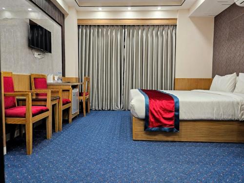 a hotel room with a bed and a table and chairs at Hotel Safa Residency - DHAKA in Dhaka