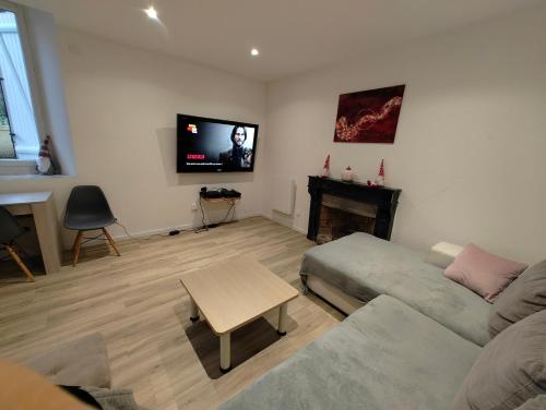 a living room with a couch and a tv on the wall at Gîte des Pleiades in Villemoirieu