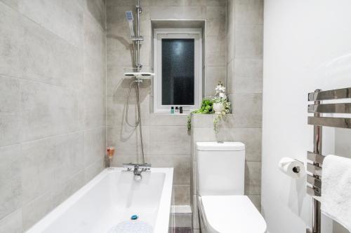 a bathroom with a tub and a toilet and a sink at 2-Bed House with Garden & Free Parking, Quiet Location, Cwmbran in Cwm-brân