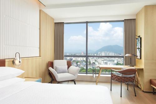 a bedroom with a bed and a desk and a window at Four Points by Sheraton Xuancheng, Jingxian in Jingxian