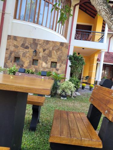 a patio with wooden tables and chairs in front of a building at Bigcity Villa - Airport Transit Hotel in Katunayake