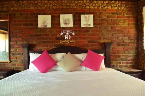 a bedroom with a bed with pink and white pillows at Real Dream Hostel in San Gil