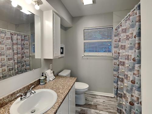 a bathroom with a sink and a toilet and a mirror at Pleasure Pier Retreat #4 in Galveston