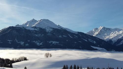 a snow covered mountain range with a layer of clouds at Apartment Steger in Mittersill