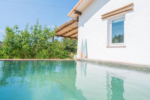 a swimming pool next to a house with a window at Casa do Vale in São Bartolomeu