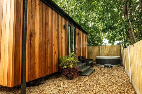 a wooden building with a tub next to a fence at Dinas Lodge with private hot tub in Llangollen