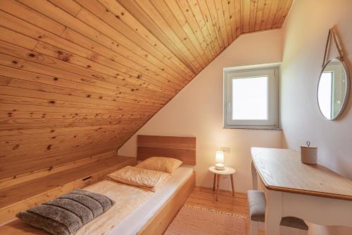 a bed in a room with a wooden ceiling at Holiday house Podhamer Boris in Presika