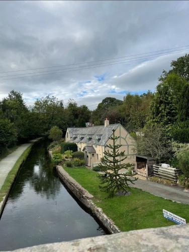 a house next to a river with a house at Penddol Cottage & Boathouse in Llangollen