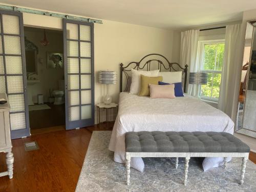 a bedroom with a large bed with a gray bench at Trouvaille House Sweet Suite in Harpers Ferry