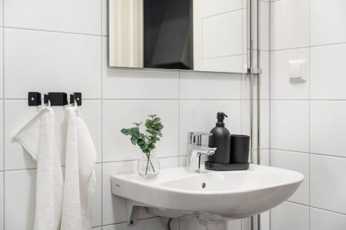 a white bathroom with a sink and a mirror at Guestly Homes - Elite Studio Apartment in Nyköping