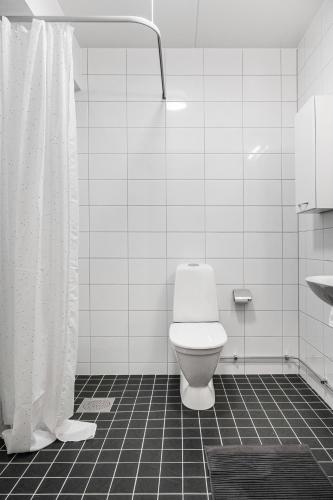 a white bathroom with a toilet and a shower at Guestly Homes - Elite Studio Apartment in Nyköping