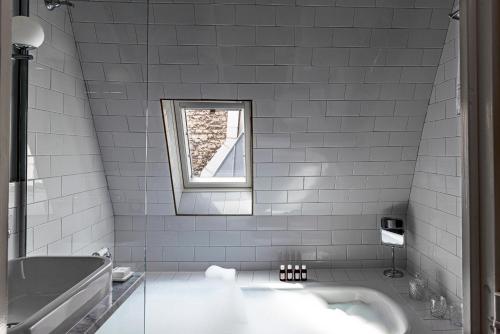a white bathroom with a tub and a window at Grand Pigalle Experimental in Paris