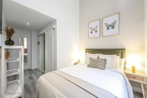 a white bedroom with a bed and two butterflies on the wall at Password to Madrid Gran Vía in Madrid