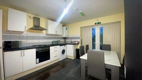 a kitchen with white cabinets and a table with a dining room at Modern Flat near StarCity, Bull Ring & M6 in Birmingham