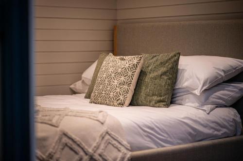 a bed with three pillows on top of it at Newydd Lodge with private hot tub in Llangollen