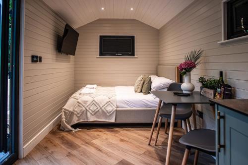 a small bedroom with a bed and a table at Newydd Lodge with private hot tub in Llangollen