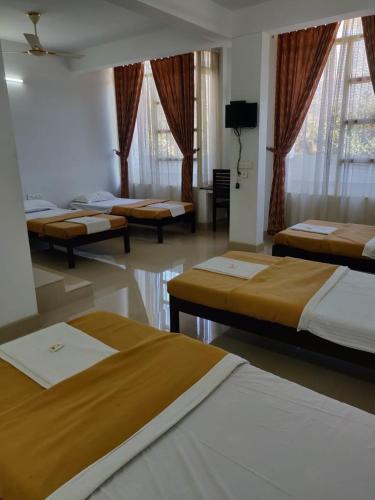 a group of beds in a room with windows at M3 Homes in Munnar