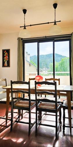 une salle à manger avec une table et des chaises et une grande fenêtre dans l'établissement L'Odyssée Vercors - Ski - Randonnée, à Villard-de-Lans