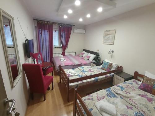 a bedroom with two beds and a red chair at Apartments & Rooms -MDL Lazić in Belgrade