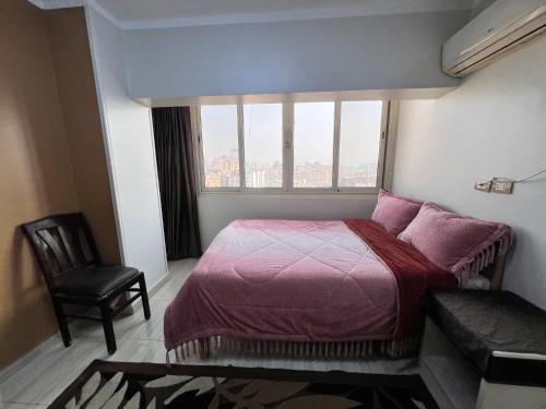 Un dormitorio con una cama y una silla y una ventana. en Isis Hostel 2, en El Cairo