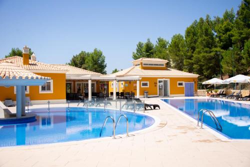 a swimming pool with chairs and a house at Castro Marim Golfe and Country Club in Castro Marim