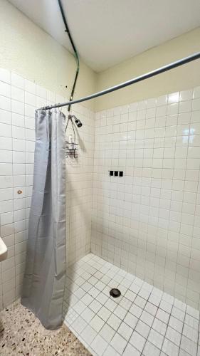 a white tiled shower with a shower curtain in a bathroom at Departamento sencillo LM in Los Mochis
