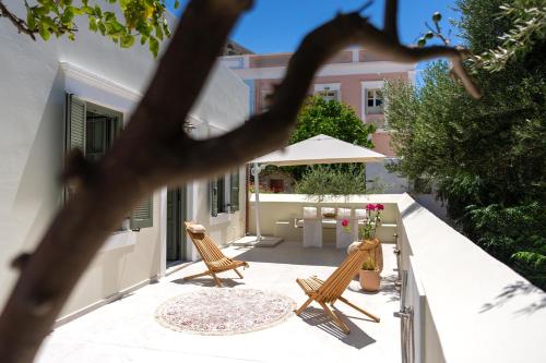 a patio with two chairs and a table and an umbrella at Nisomar Suites in Symi