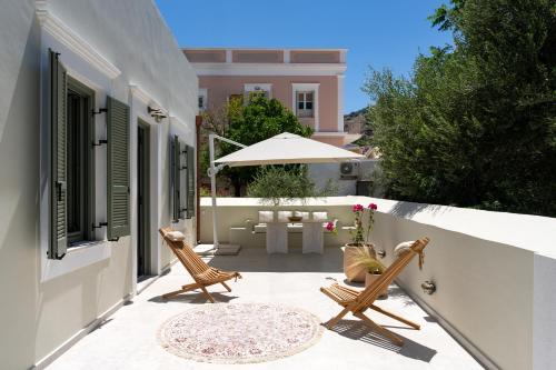 a patio with two chairs and a table and an umbrella at Nisomar Suites in Symi