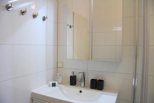 a white bathroom with a sink and a mirror at Nollendorf Apartments in Berlin