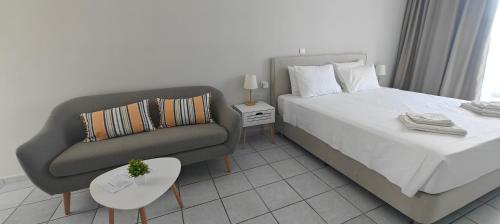 a bedroom with a bed and a couch and a chair at Marina Studio Appartments in Kardamaina