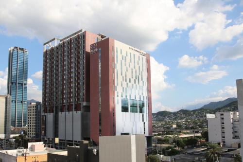 a tall red and white building in a city at City Express Plus by Marriott Monterrey Centro in Monterrey