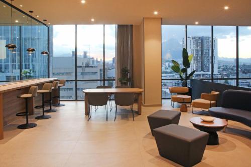 a hotel lobby with a bar and chairs and windows at City Express Plus by Marriott Monterrey Centro in Monterrey