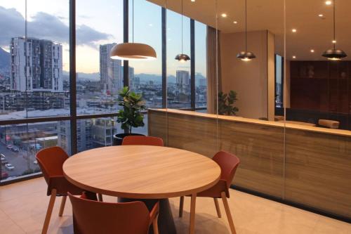 a table and chairs in a room with windows at City Express Plus by Marriott Monterrey Centro in Monterrey