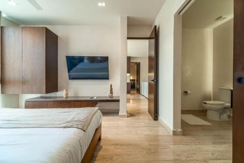 a bedroom with a bed and a bathroom with a toilet at 3BR Penthouse with Private Plunge Pool in Tulum