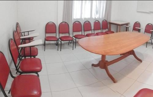 a conference room with a wooden table and red chairs at Hotel Linhatur in Linhares