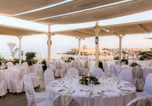 a wedding reception at the beach with white tables and chairs at Radisson Blu Resort, Malta St. Julian's in St Julian's