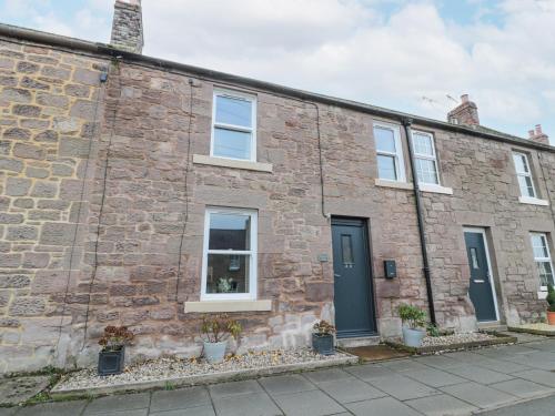 an old brick house with white windows and blue doors at Castle Keep in Berwick-Upon-Tweed