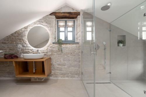 a bathroom with a sink and a glass shower at Beeindruckende Steinfinca mit privatem Salzwasserpool, Panoramablick aufs Meer, Grill in Orbani