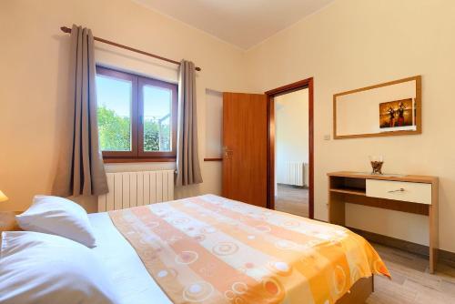 a bedroom with a bed and a desk and a window at Faszinierendes Ferienhaus mit Privatpool, Volleyballfeld, Fussballplatz, Trampolin beim bekannten Radweg Parenzana in Vižinada