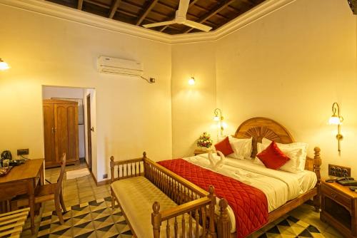 a bedroom with a bed and a table and a desk at Amritha Heritage in Trivandrum