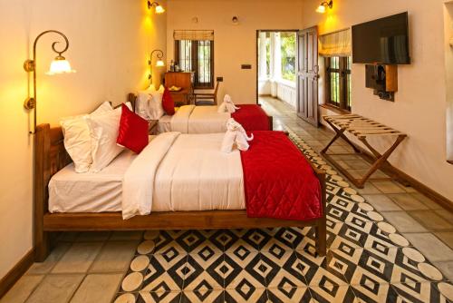a bedroom with two beds with red and white sheets at Amritha Heritage in Trivandrum