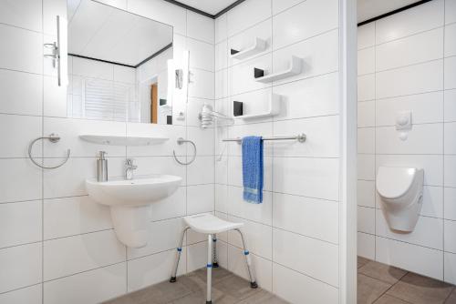 a white bathroom with a sink and a toilet at Landhaus Familie Allgeier in Holtgast