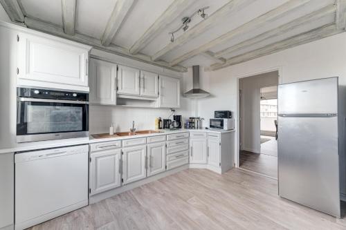 une cuisine blanche avec des armoires et des appareils blancs dans l'établissement Le Cosy, à Saint-Priest