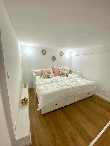 ein weißes Schlafzimmer mit einem Bett mit rosa Kissen in der Unterkunft Studio cosy Nice in Nizza
