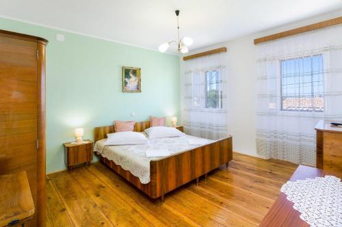 a bedroom with a bed and two windows at Mediterranes Steinhaus mit grosser Terrasse, Aussendusche, Privatpool, Babybett, Waschmaschine in Grižane