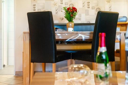 a table with two black chairs and a bottle of wine at Landhaus Familie Allgeier in Holtgast