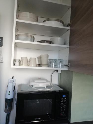 a microwave in a kitchen with plates and dishes at Zee en Strand in De Panne