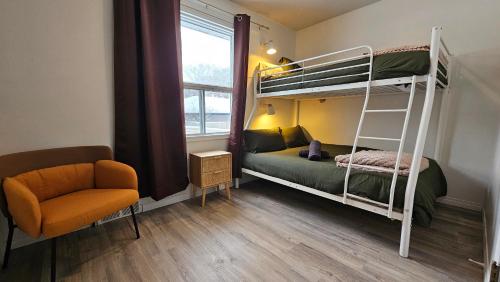 a small room with a bunk bed and a chair at Retro Retreat - 3bdr, 1 bath, close to city center in Edmonton