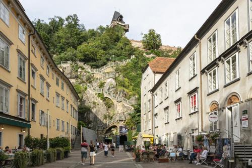 a group of people walking down a street at Emerald Design - Historic City Center with Free Parking & Panoramic View by HERO HOMES in Graz